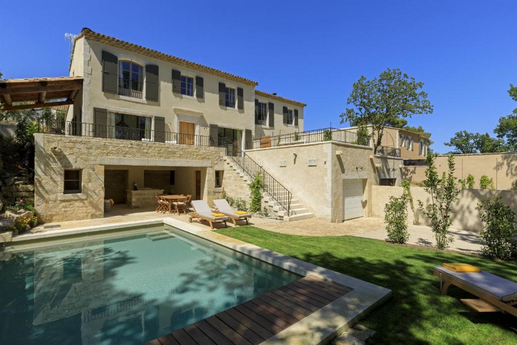 a house with a swimming pool in front of a yard at Les Bastides du Mas de l'Amarine in Saint-Rémy-de-Provence