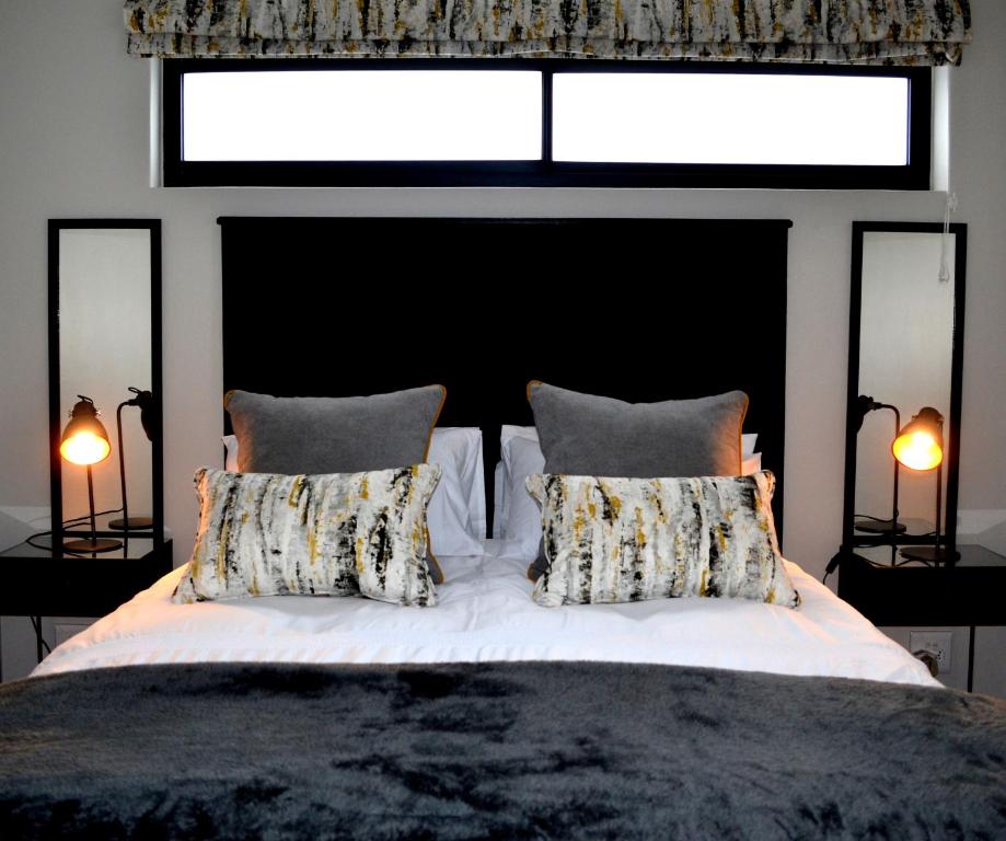 a bedroom with a white bed with two pillows at Columbine Place in Durbanville