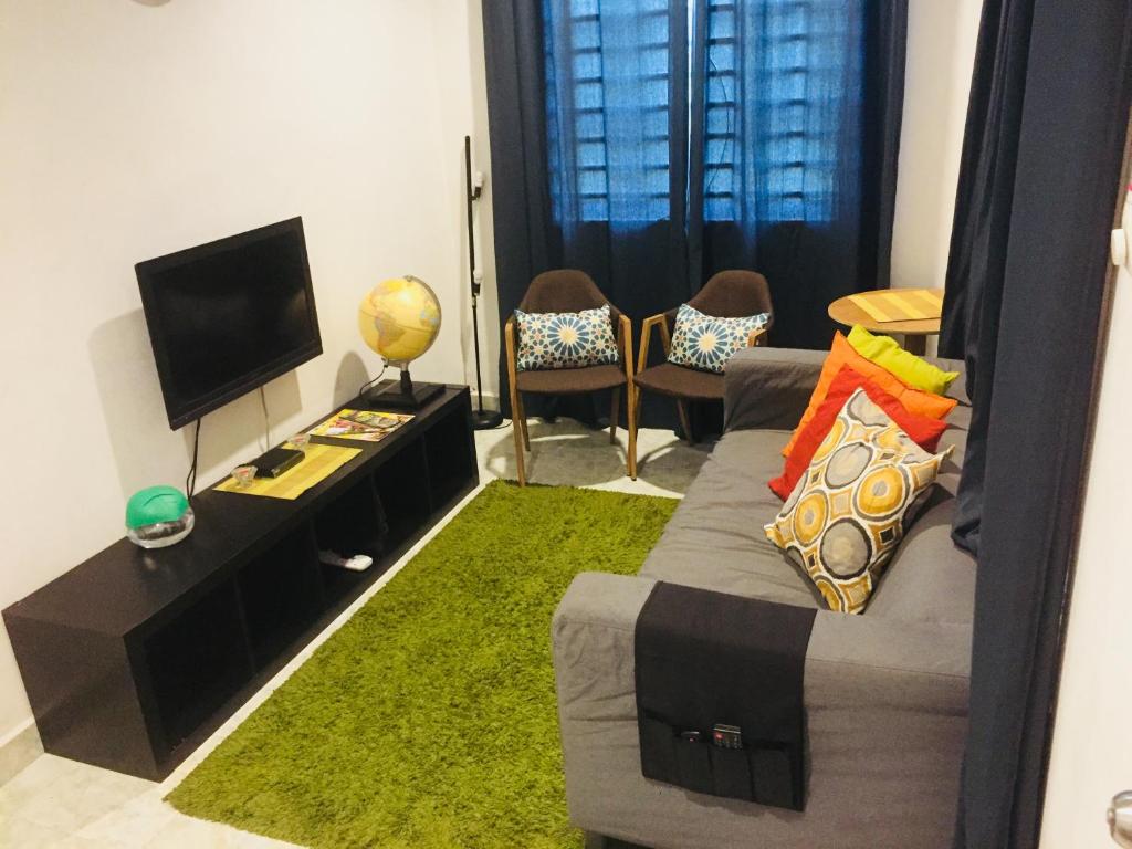 salon z kanapą i telewizorem z płaskim ekranem w obiekcie The Idealist Guesthouse w mieście Pantai Cenang