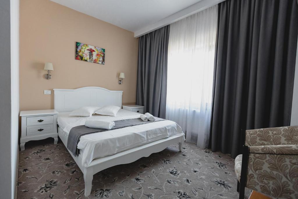 1 dormitorio con cama blanca y ventana en Hotel Cristian, en Afumaţi