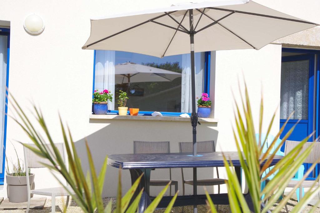 a table with an umbrella in front of a house at Maison "Ouessant" Pays des Abers in Plouguerneau