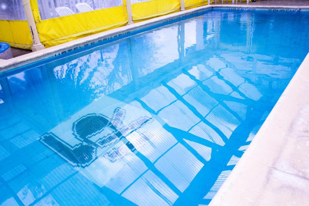 una piscina con una silla en el agua en San Remo Palace Hotel en Villa Gesell