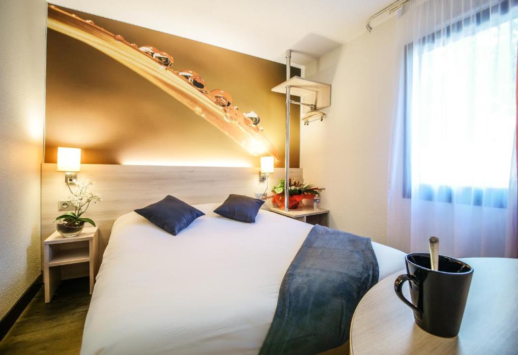 een hotelkamer met een groot wit bed met blauwe kussens bij Hôtel Inn Design Resto Novo Montargis in Villemandeur