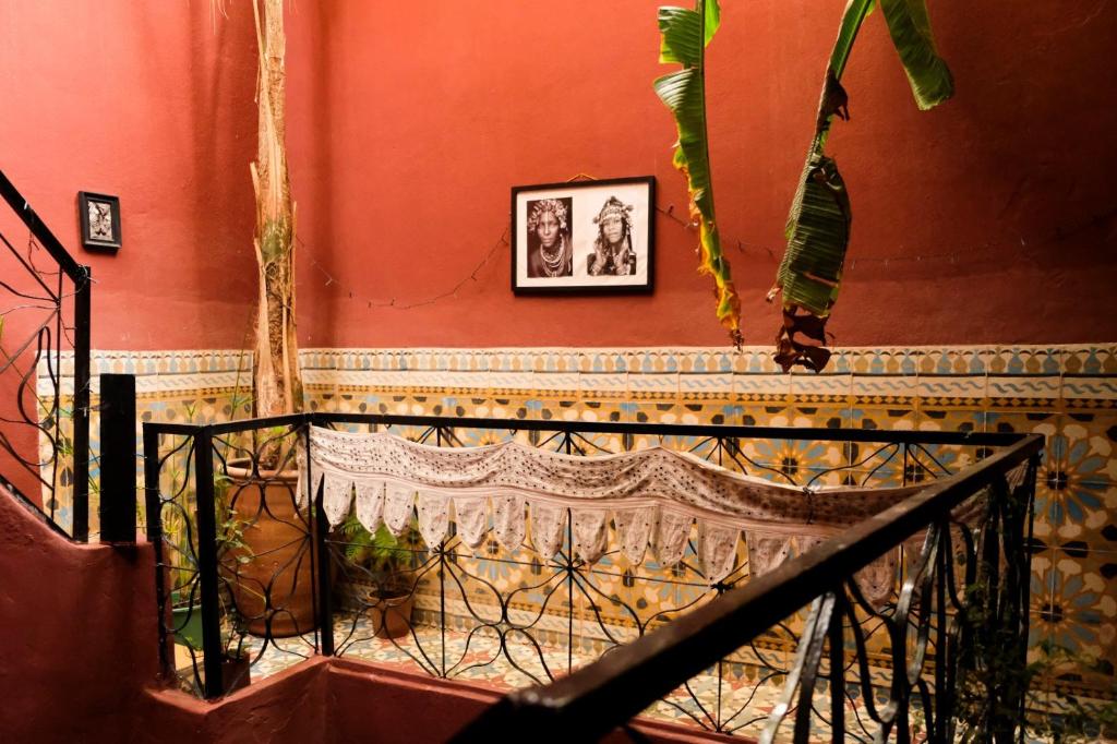 - un escalier dans une pièce avec un mur rouge orné de plantes dans l'établissement Riad Kainos, à Marrakech