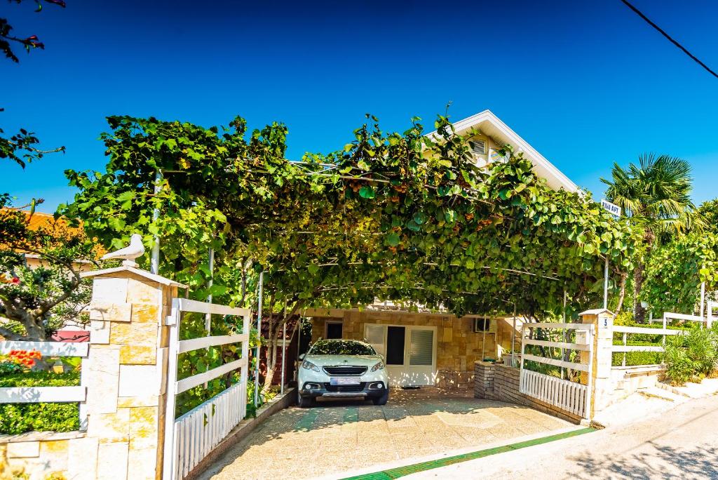 een auto geparkeerd voor een huis met een bos druiven bij Kiwi apartments in Gornji Karin