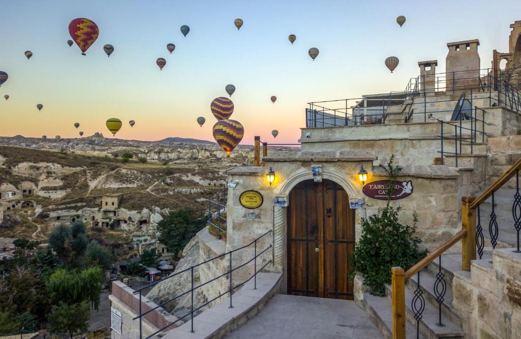 um grupo de balões de ar quente sobrevoando um edifício em Fairyland Cave Hotel em Goreme