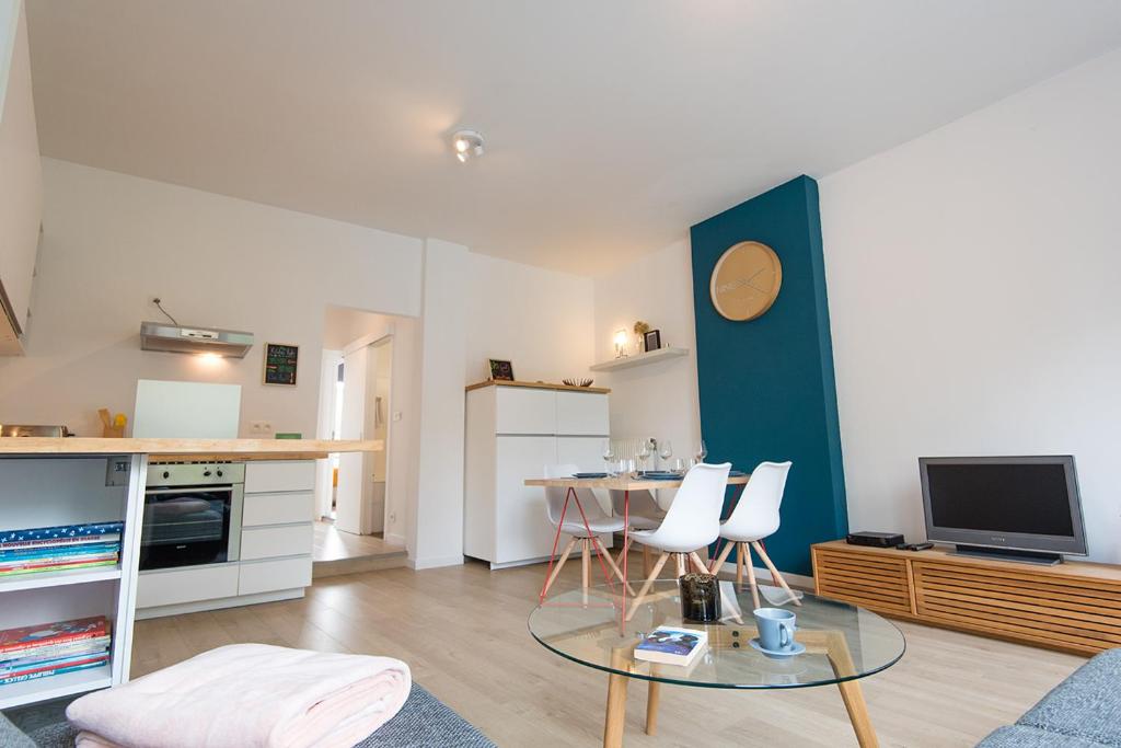 a living room with a table and chairs and a kitchen at La petite Naimette in Liège