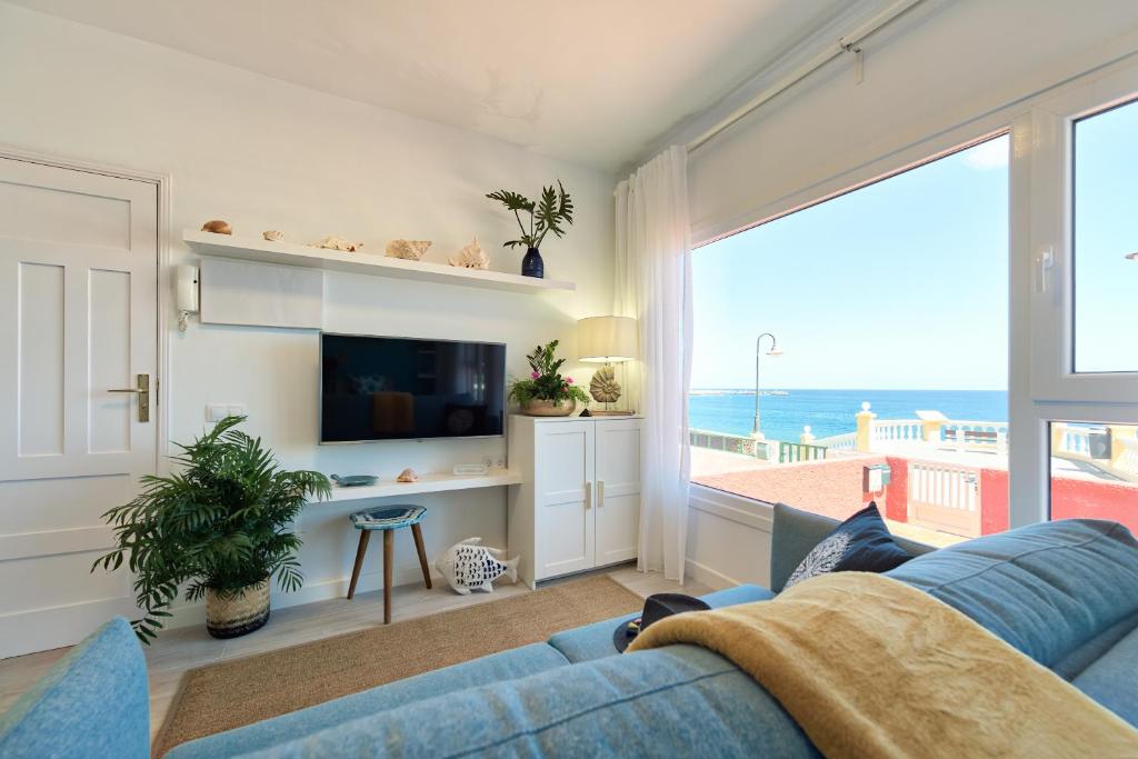 uma sala de estar com um sofá azul e vista para o oceano em Casa Antonia by the beach Melenara em Melenara