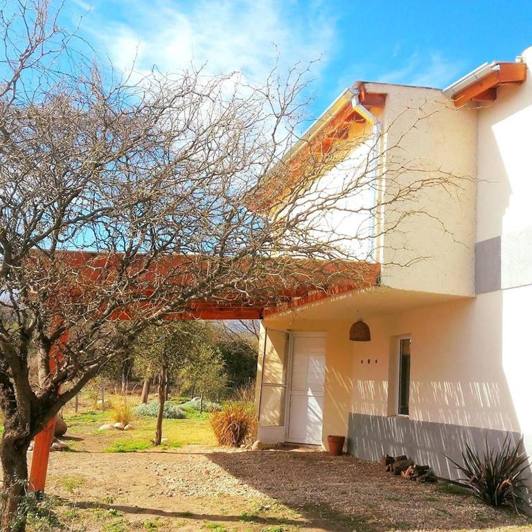 a white house with a tree in front of it at Sueño del Champaquí in Villa Las Rosas