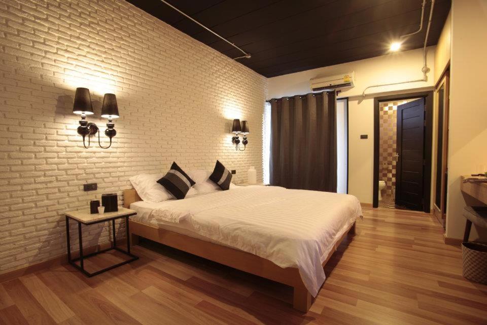 een slaapkamer met een groot bed en een bakstenen muur bij Diary Suite in Nakhon Pathom