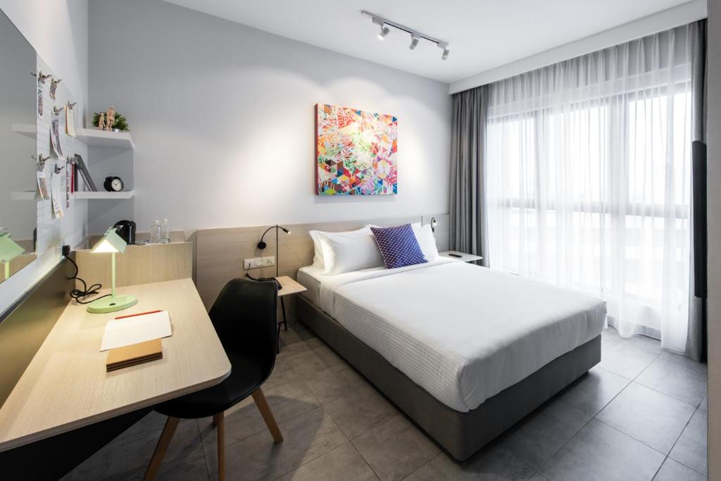 a hotel room with a bed and a desk and a desk at The Canvas Hotel in Klang