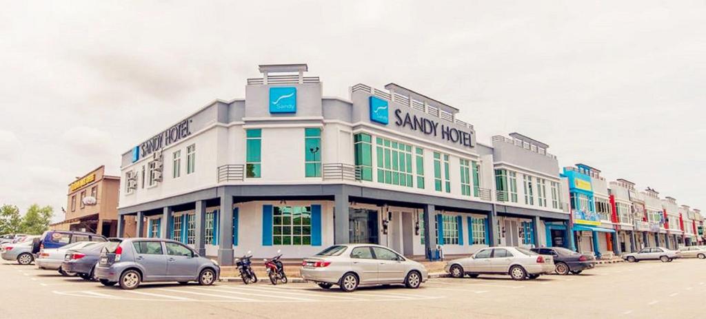 a large building with cars parked in a parking lot at Sandy Hotel Malacca in Melaka