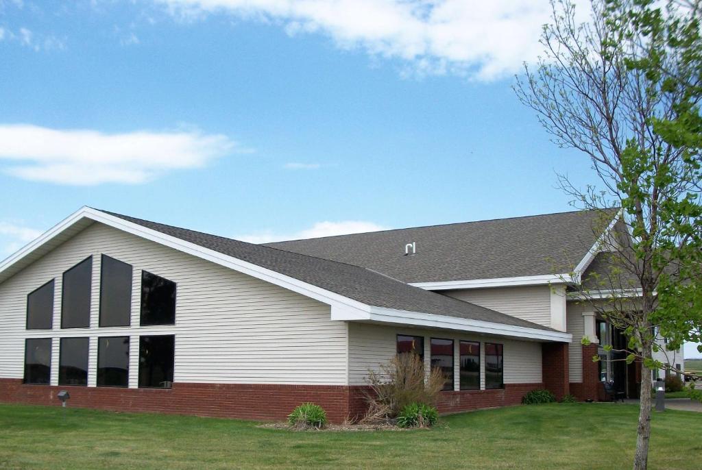 a white and red house with a roof at AmericInn by Wyndham Beulah in Beulah