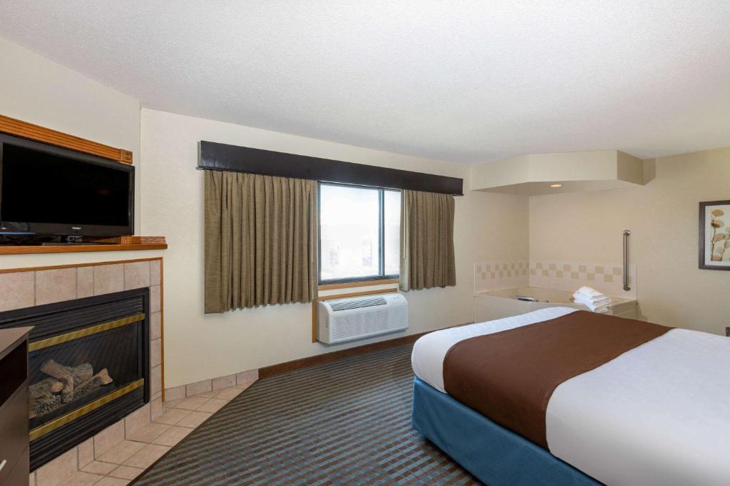 リンカーンにあるAmericInn by Wyndham Lincoln Northのベッドと暖炉のあるホテルの部屋