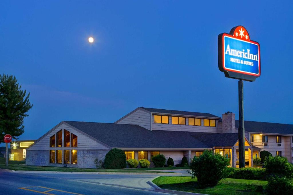 a motel with a sign in front of a building at AmericInn by Wyndham Grundy Center in Grundy Center