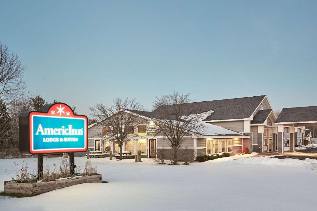 a sign in the snow in front of a motel at AmericInn by Wyndham Douglas/Saugatuck in Saugatuck