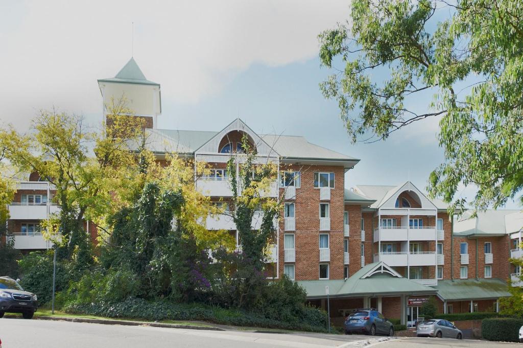 a large building with a tree in front of it at Nesuto Pennant Hills in Pennant Hills