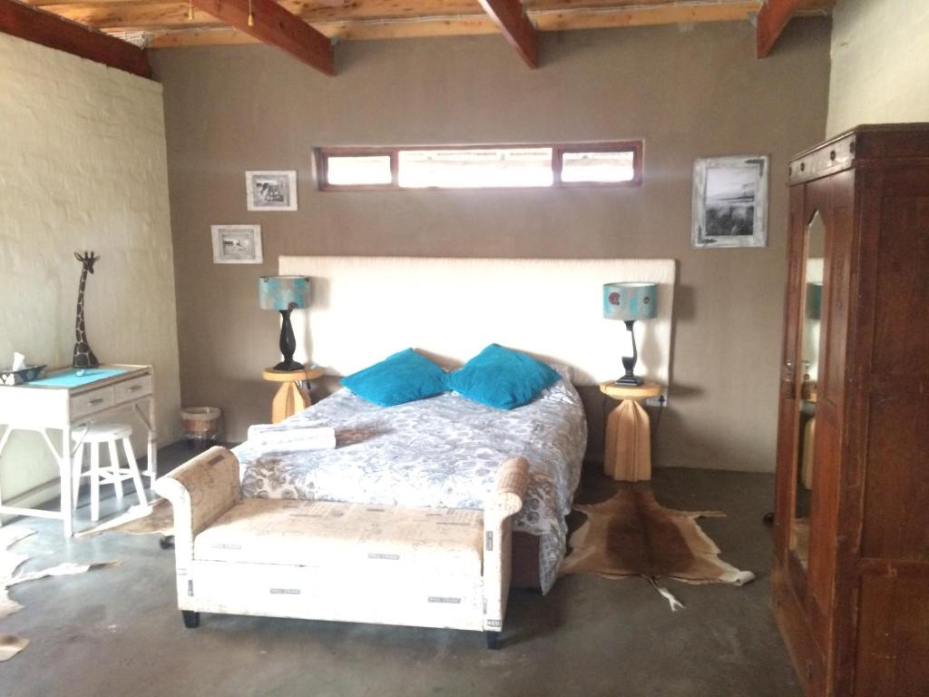a bedroom with a bed and a desk and a window at Olievenhoutsrus Guest- and Game Farm in Vaalwater
