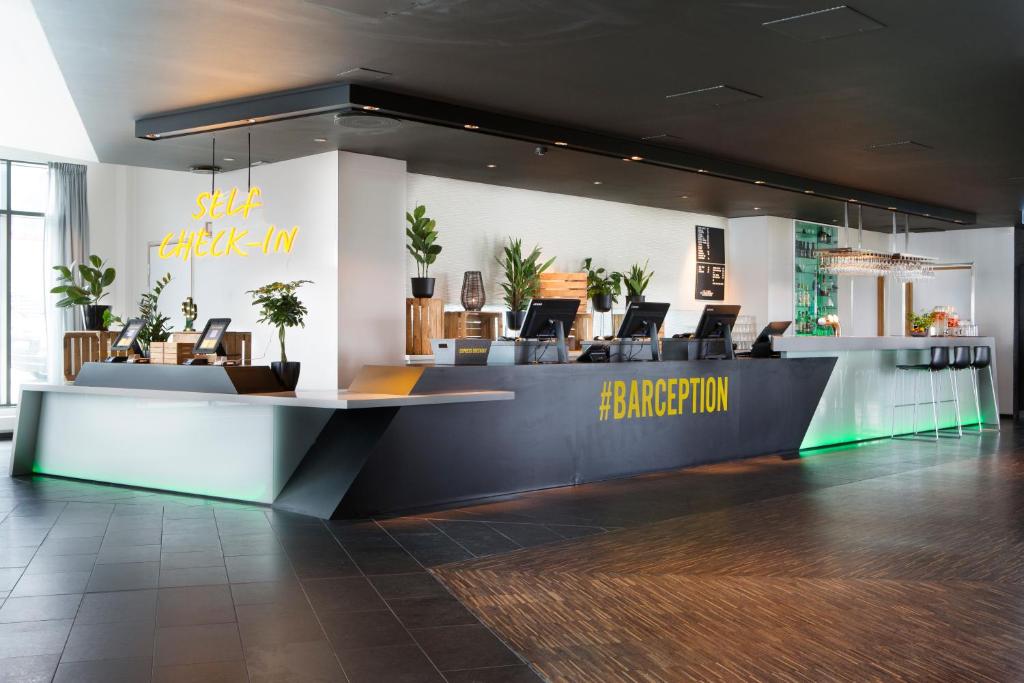 a lobby with a reception desk with chairs and plants at Comfort Hotel RunWay in Gardermoen