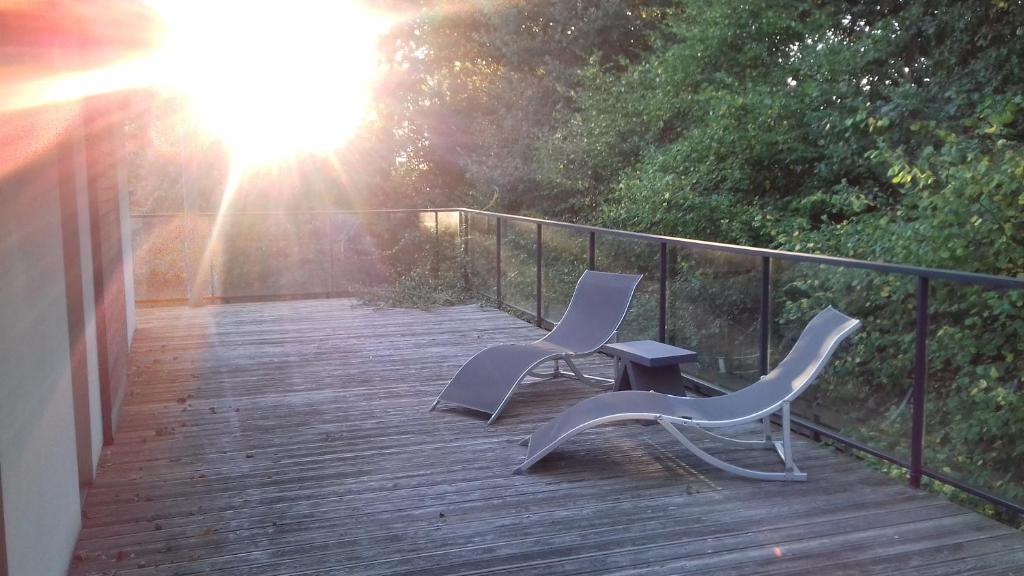 2 sillas y una mesa en una terraza de madera en Maison passive et d'architecte, en Treillières