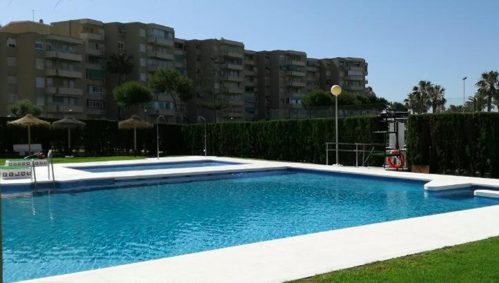 een groot zwembad in een tuin met enkele gebouwen bij Apto frente PLAYA LA CALA Parking gratuito in Málaga