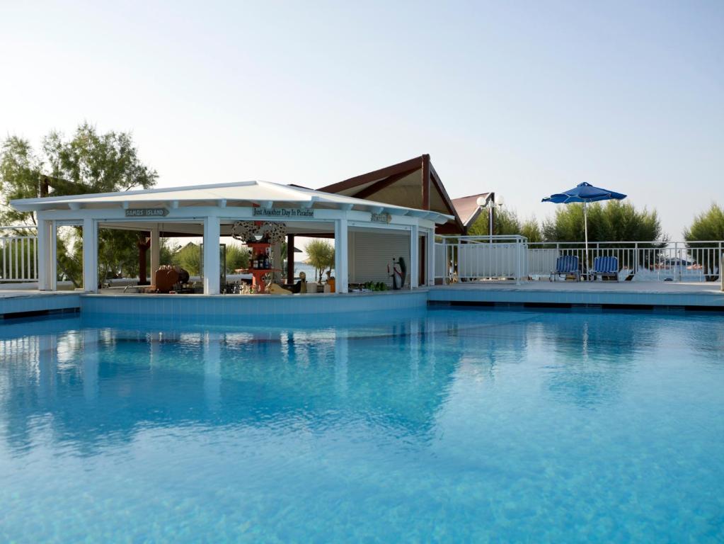 a large blue swimming pool with a gazebo at Kouros Seasight Hotel in Pythagoreio