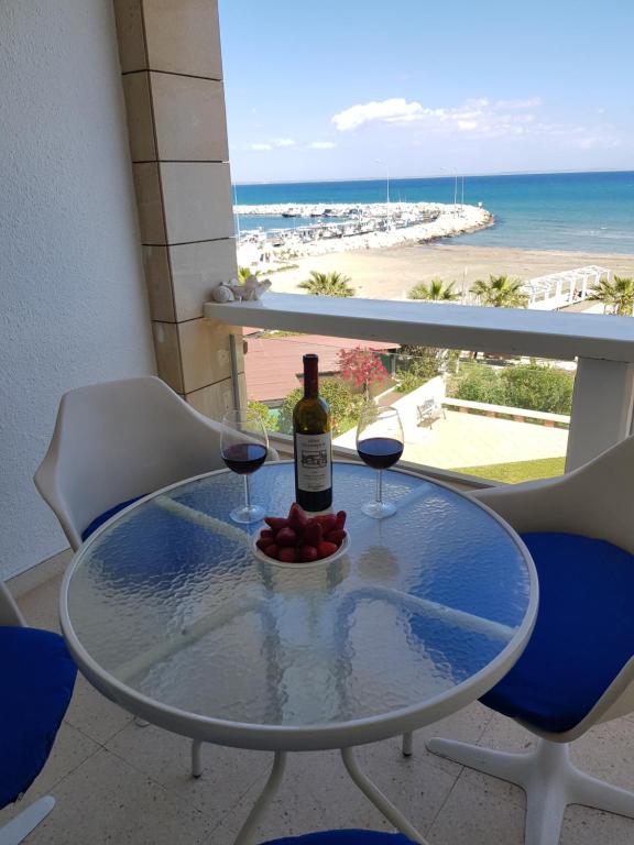 ラルナカにあるHaig's Dream Flat On The Beachのワイングラス2杯とワイン1本付きのテーブル