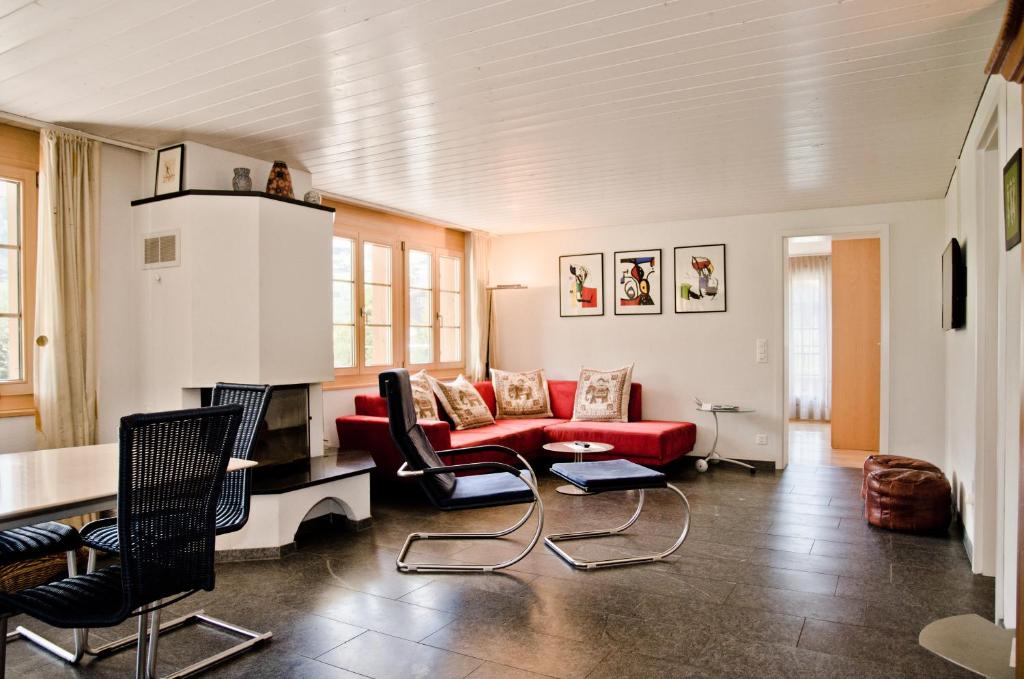 sala de estar con sofá rojo y sillas en Apartment Atlanta - GRIWA RENT AG, en Grindelwald