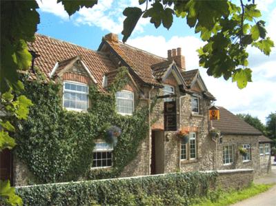 a large brick house with ivy growing on it at The Hunters Rest Inn in Clutton