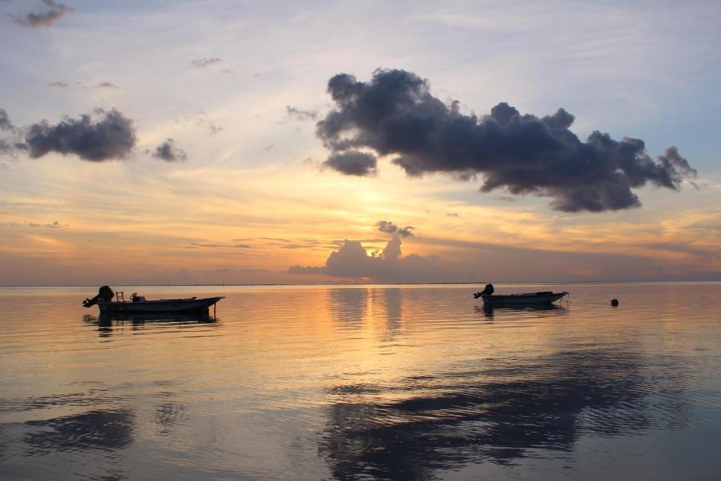 two boats sitting in the water at sunset at Fare Edith Moorea in Haapiti