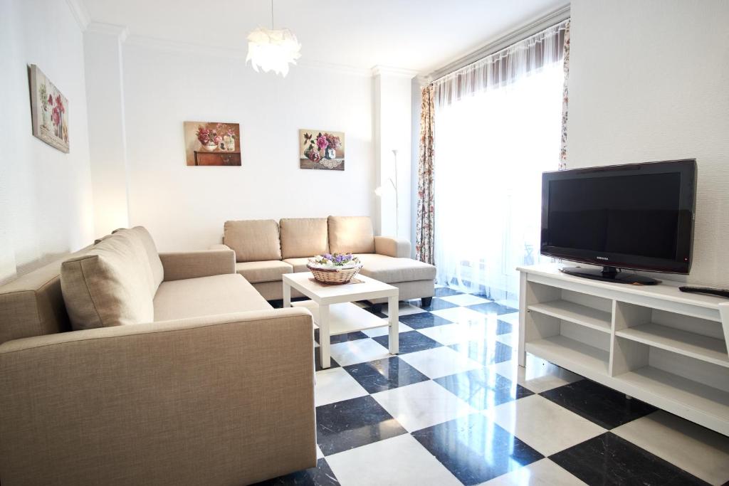 uma sala de estar com um sofá e uma televisão em Nervion Paradise em Sevilha