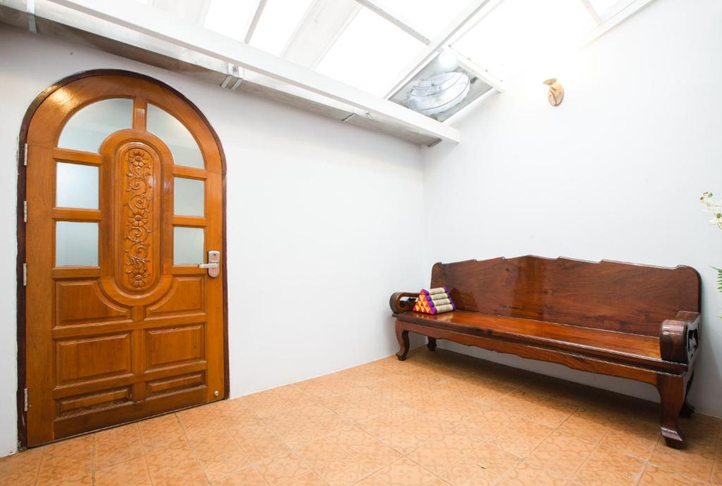 A carved wooden door and long wooden bench face a bright tiled hall.