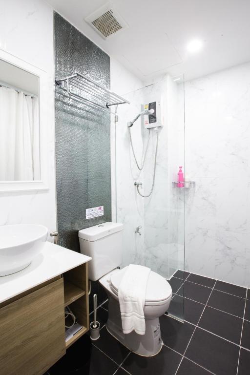 A compact marble-look bathroom with a glass-enclosed shower and separate toilet.