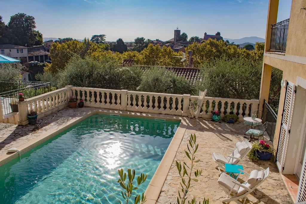 uma piscina com cadeiras e uma cerca em La Muse du Paradis em Montauroux