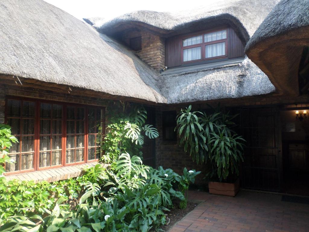 a thatch roofed house with windows and plants at Foundry Guest Lodge in Pretoria
