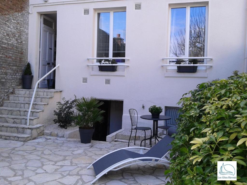 Casa blanca con mesa y sillas en el patio en Les Gîtes Havrais, en Le Havre