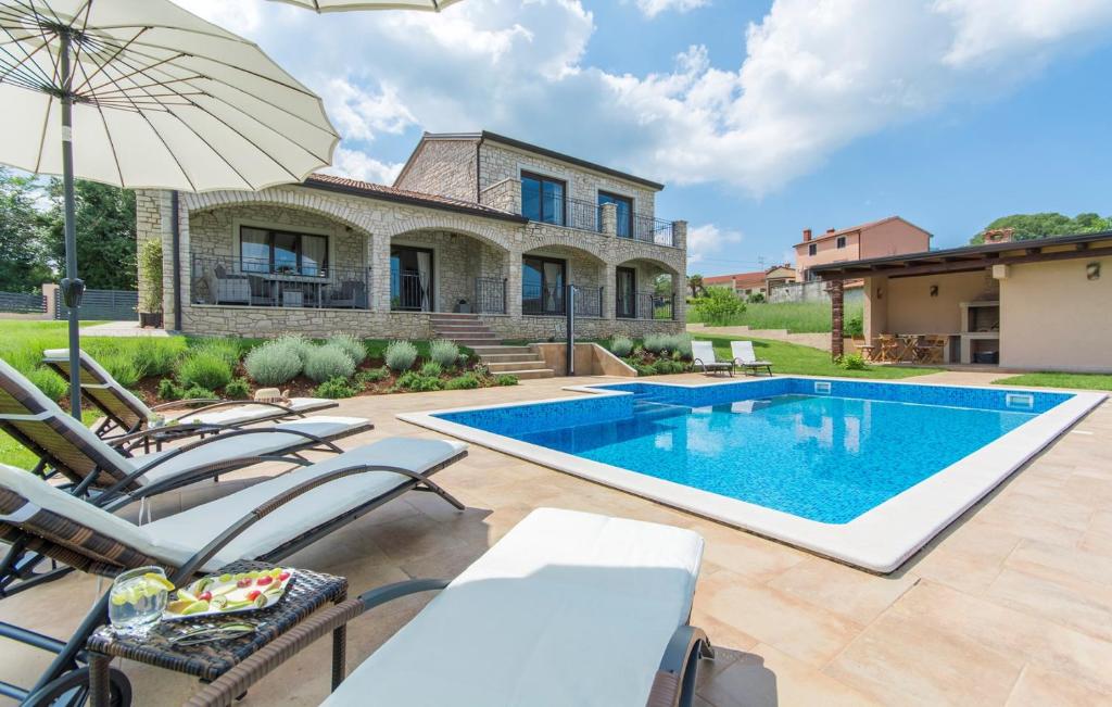 een zwembad voor een huis met stoelen en een parasol bij Villa Roma in Baderna