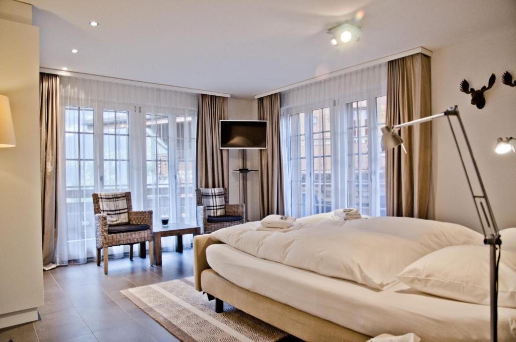 1 dormitorio con 1 cama grande, escritorio y sillas en Apartment Felix - GRIWA RENT AG en Grindelwald