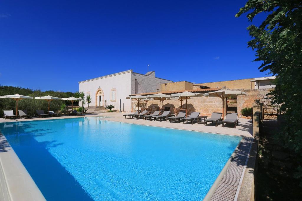 a large blue swimming pool with chairs and umbrellas at Antica Masseria Pescu in Presicce