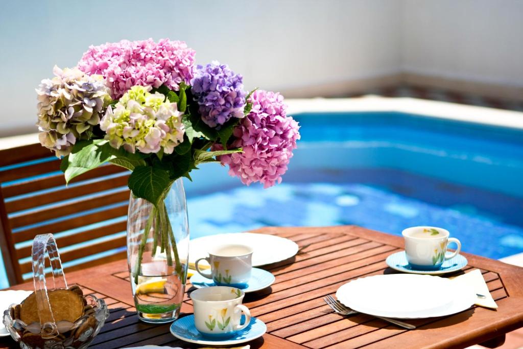 un jarrón de flores en una mesa junto a una piscina en Apartments Veramenta, en Cavtat