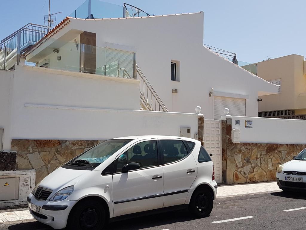 un coche blanco estacionado en un estacionamiento frente a una casa en Casa Julia en Playa de las Americas