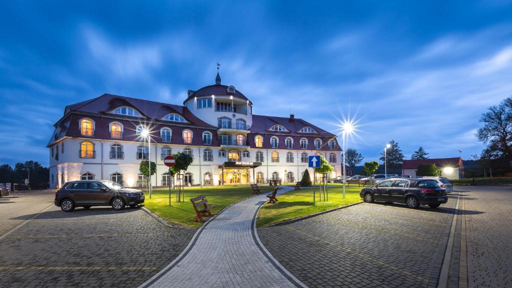 Hotel Woiński Spa في لوبنيفيتسا: مبنى كبير فيه سيارات تقف امامه
