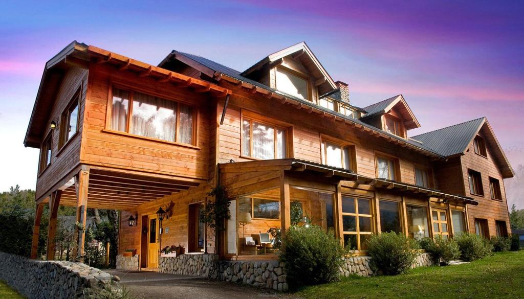 una gran casa de madera con muchas ventanas en Hosteria El Establo en Villa La Angostura