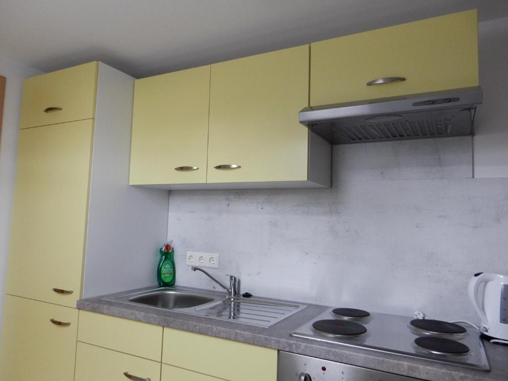 eine Küche mit gelben Schränken und einem Waschbecken in der Unterkunft Ferienwohnung Gänseblümchen in Wartenburg