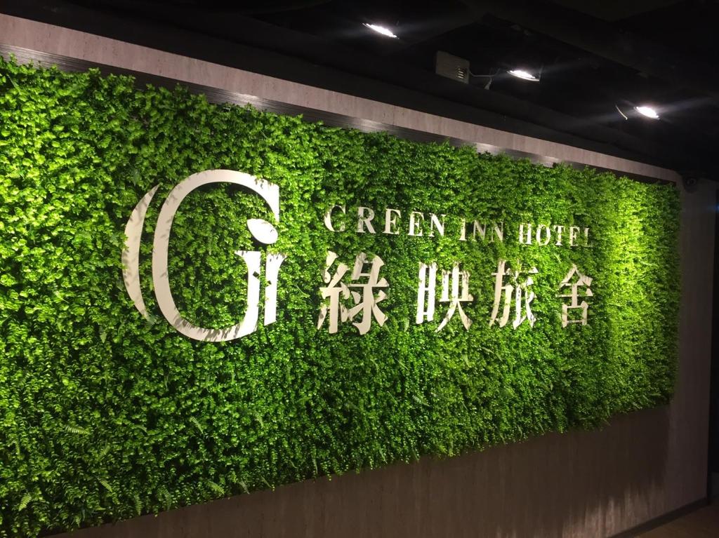 a green wall with the words green in house at Greeninn Hotel in Taipei