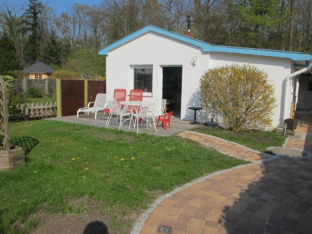 ein weißes Haus mit einem Tisch und Stühlen im Hof in der Unterkunft Ferienhaus Fischerhus Hans in Timmendorfer Strand