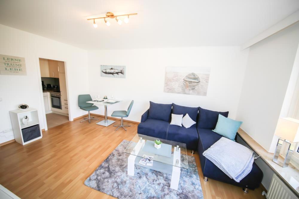a living room with a blue couch and a table at Ferienwohnung Koje 117 im Haus Carpe Diem in Niendorf