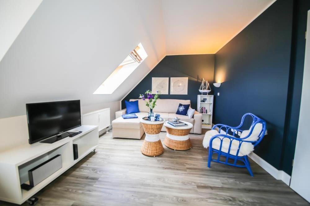 een woonkamer met blauwe stoelen en een tv bij Ferienwohnung Nordnordost in Timmendorfer Strand