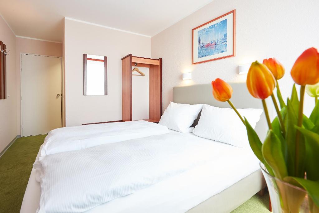 Hotel Anhalt في Brehna: غرفة نوم مع سرير أبيض مع زهور برتقالية