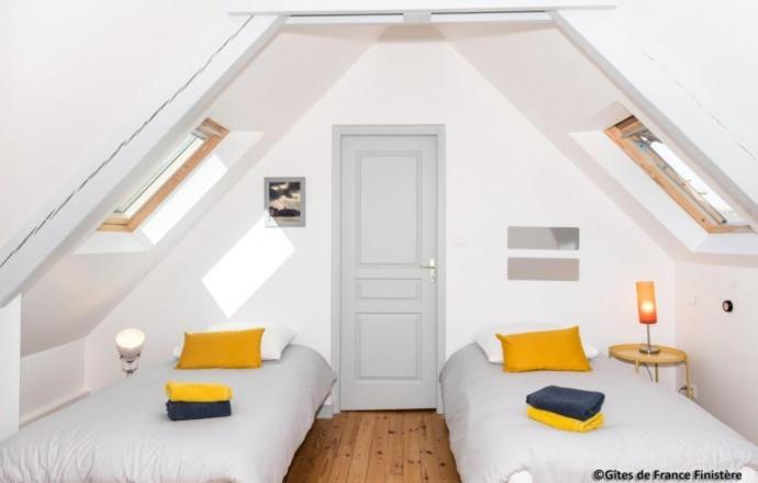 two beds in a attic room with white walls and yellow pillows at Le Gîte du Port in Roscoff